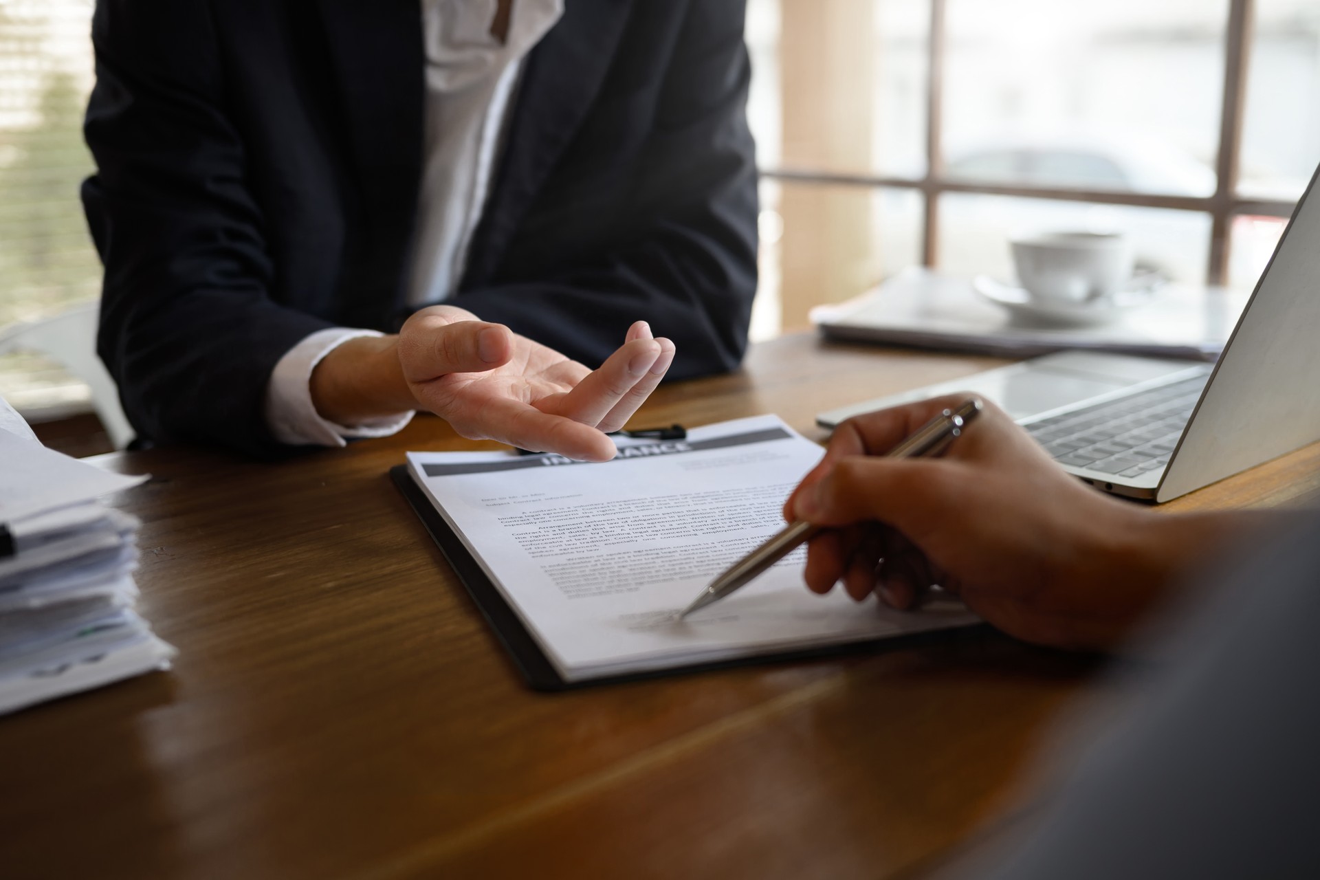 Cropped shot of insurance agent showing where to sign a contract during meeting